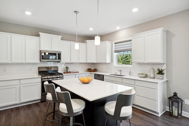 kitchen featuring a breakfast bar area, stainless steel appliances, a kitchen island, a sink, and decorative backsplash