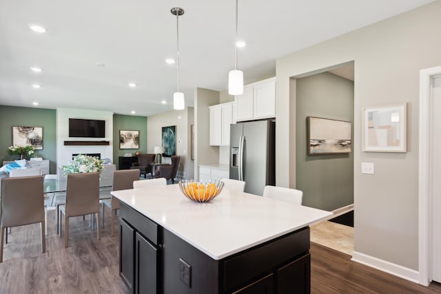 kitchen with white cabinets, dark wood-style floors, a center island, light countertops, and stainless steel refrigerator with ice dispenser