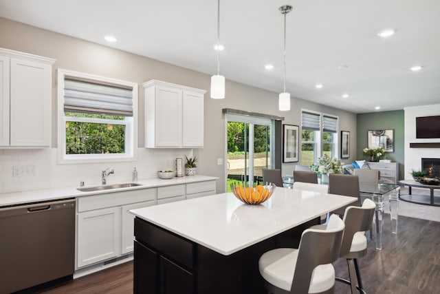 kitchen with tasteful backsplash, open floor plan, light countertops, stainless steel dishwasher, and a sink