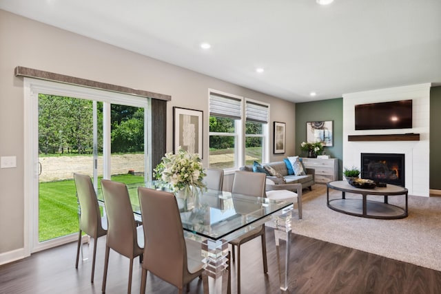 dining space with dark wood-style floors, a fireplace, baseboards, and recessed lighting