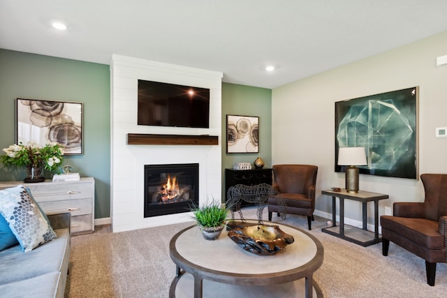 carpeted living area featuring a large fireplace, baseboards, and recessed lighting