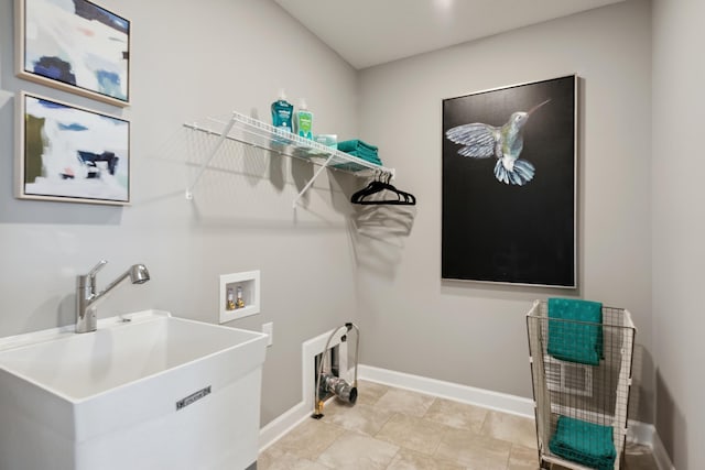 laundry room featuring laundry area, baseboards, washer hookup, and a sink