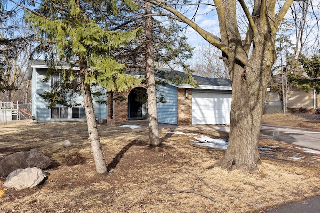 view of front of property featuring driveway, brick siding, an attached garage, and fence