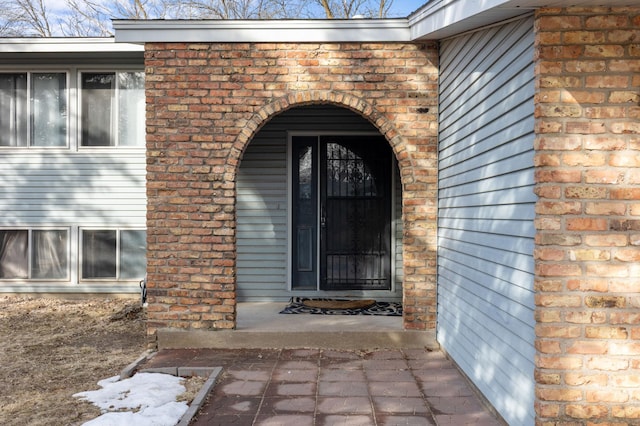 view of exterior entry featuring brick siding