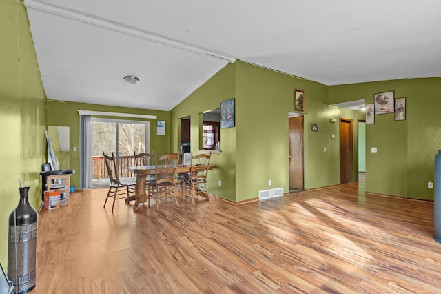 dining room featuring visible vents, lofted ceiling, and wood finished floors