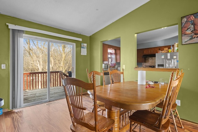 dining area featuring visible vents, lofted ceiling, and wood finished floors