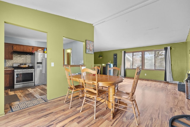 dining room with light wood-style flooring and vaulted ceiling