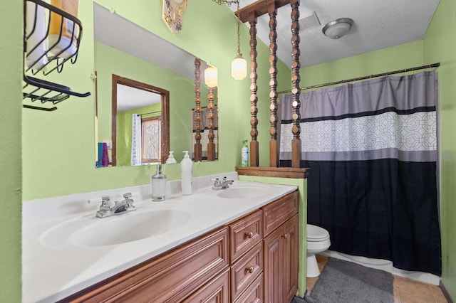 bathroom featuring tile patterned floors, double vanity, toilet, and a sink