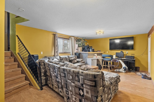 living area with stairway, a textured ceiling, and wood finished floors