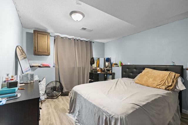 bedroom featuring a textured ceiling, visible vents, and light wood-type flooring