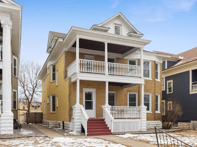 view of front of property with a balcony, covered porch, and brick siding