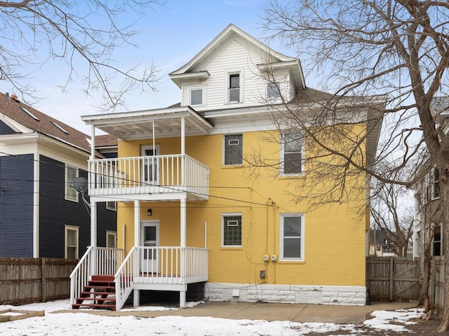 view of front facade featuring brick siding, fence, and a balcony