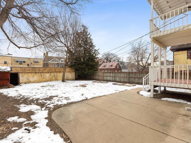 snowy yard featuring a fenced backyard and a patio