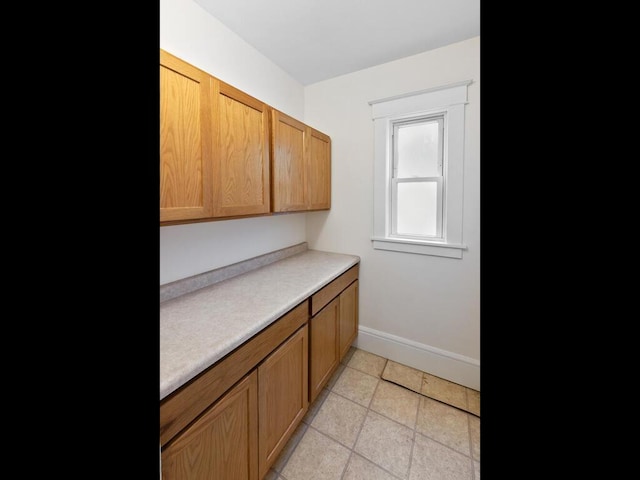 kitchen featuring brown cabinetry, baseboards, and light countertops