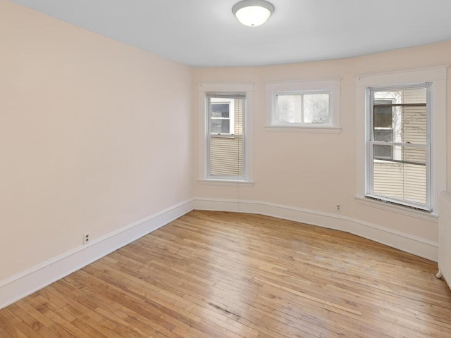 unfurnished room featuring radiator, baseboards, and light wood finished floors