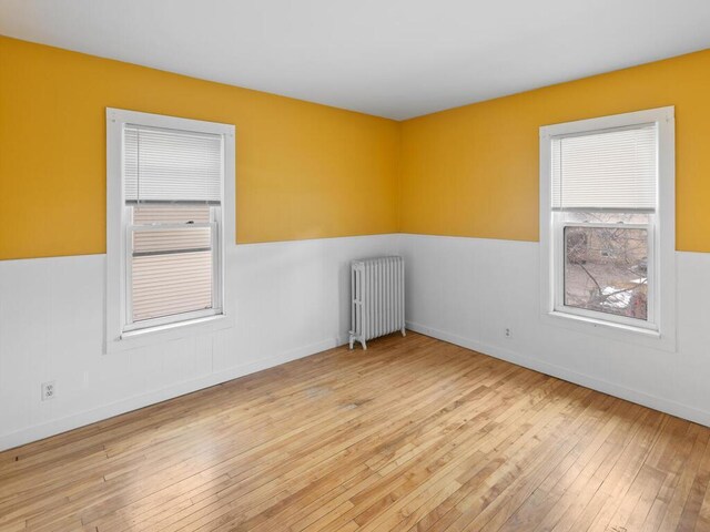 unfurnished room with radiator heating unit, baseboards, and hardwood / wood-style floors