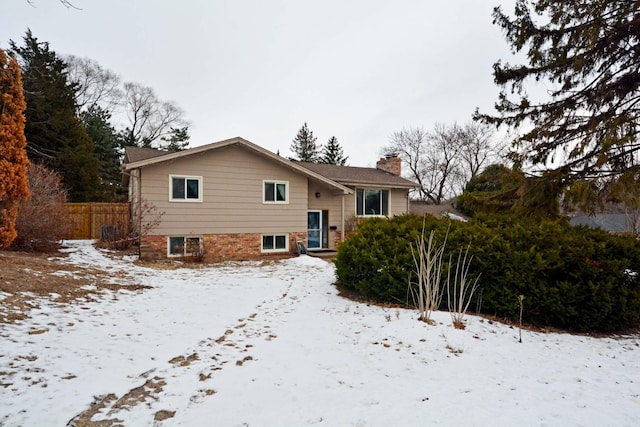 snow covered rear of property featuring fence and a chimney