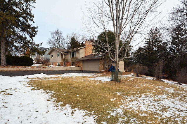 snow covered property featuring a garage and a chimney