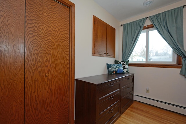 bedroom featuring light wood finished floors and a baseboard radiator