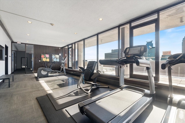 gym featuring a textured ceiling, a view of city, recessed lighting, carpet floors, and expansive windows