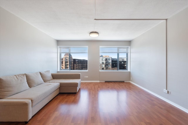 unfurnished living room featuring a textured ceiling, baseboards, and wood finished floors