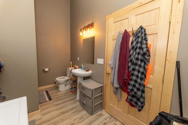 bathroom featuring baseboards, a sink, toilet, and wood finished floors