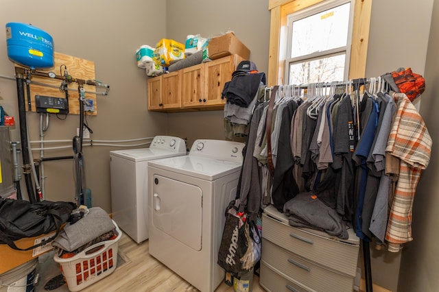 washroom featuring light wood-style floors, cabinet space, and washer and clothes dryer