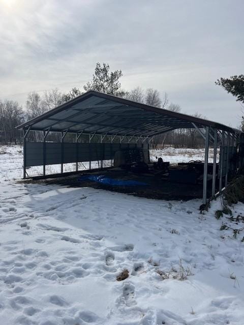 snow covered parking area featuring a carport