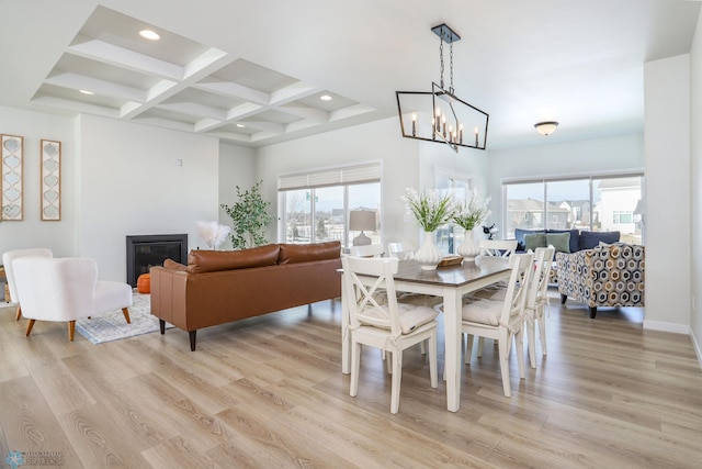 dining space with light wood finished floors, beam ceiling, coffered ceiling, and a wealth of natural light