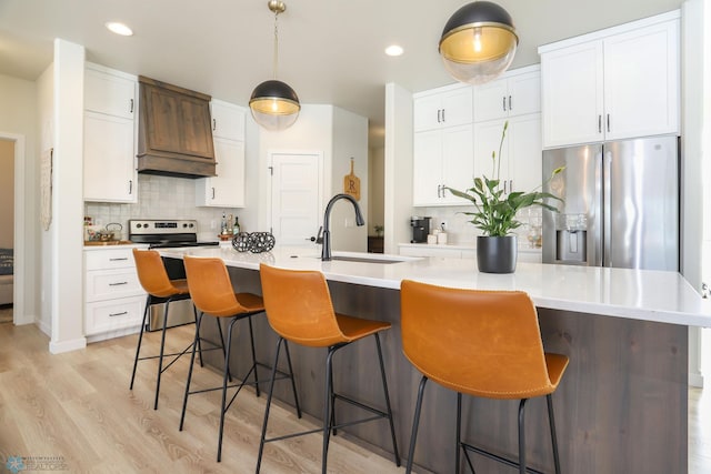 kitchen featuring stainless steel appliances, tasteful backsplash, a sink, and white cabinets