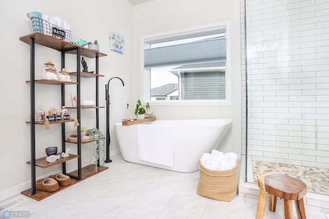 bathroom featuring a stall shower, a freestanding tub, and baseboards