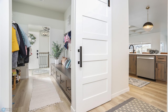 mudroom featuring light wood-style floors, a barn door, a sink, and an inviting chandelier