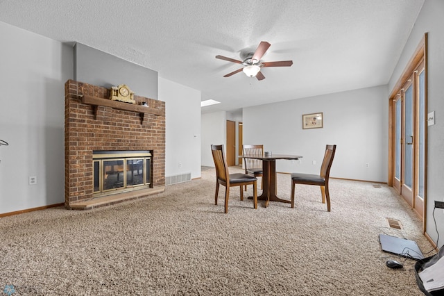 dining area featuring carpet floors, visible vents, a fireplace, and a textured ceiling