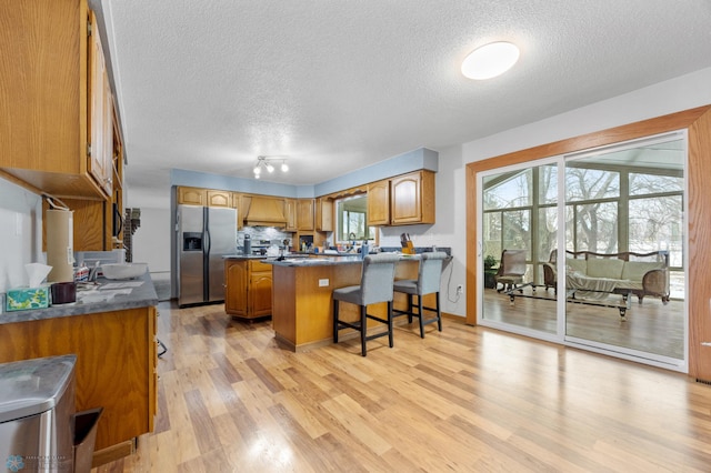 kitchen with a peninsula, a breakfast bar area, stainless steel fridge, and a wealth of natural light