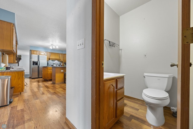 bathroom featuring toilet, tasteful backsplash, wood finished floors, and vanity