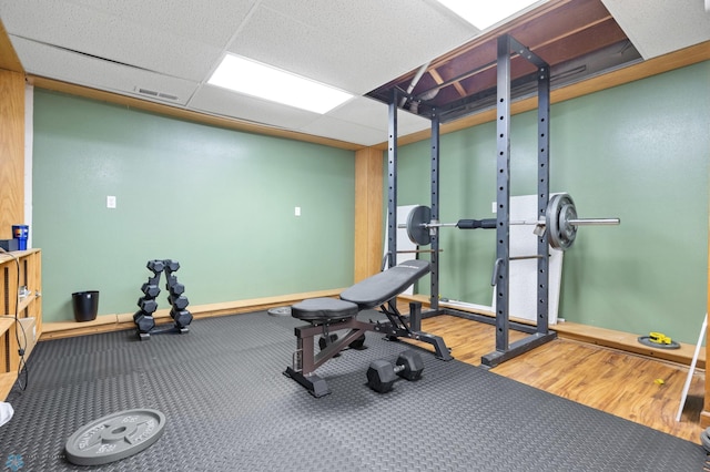 exercise room featuring a paneled ceiling, visible vents, and wood finished floors