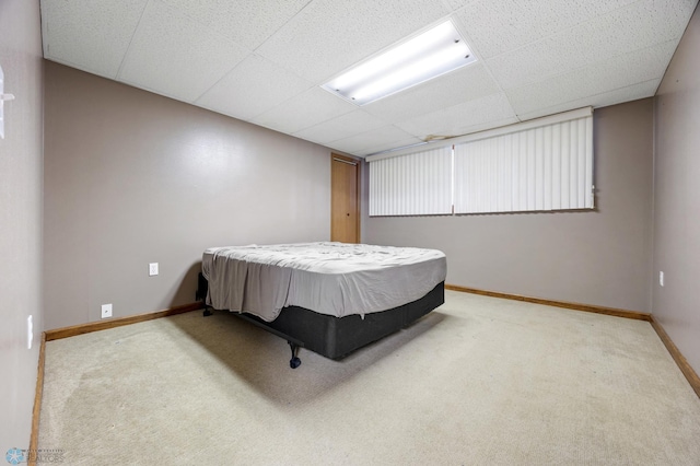 bedroom with carpet floors, a paneled ceiling, and baseboards