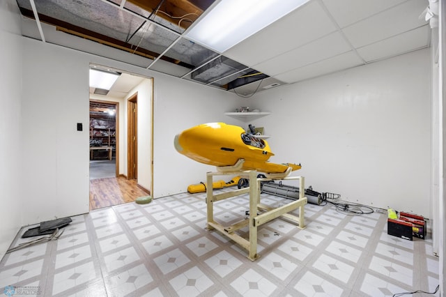 workout room featuring light floors and a drop ceiling