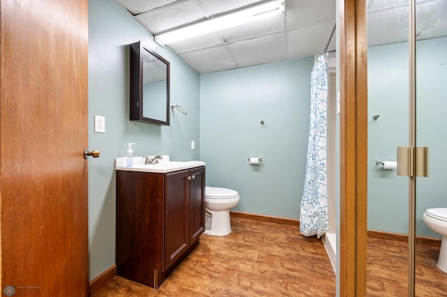 full bathroom with a paneled ceiling, toilet, a shower with shower curtain, vanity, and baseboards