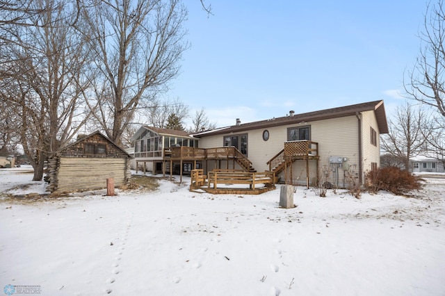 snow covered property featuring a deck, a sunroom, and stairway