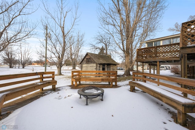 snow covered deck featuring an outdoor fire pit and an outdoor structure