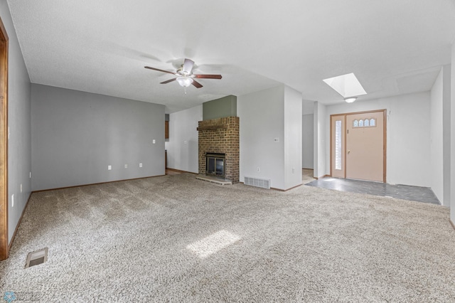 289 2nd St SW, Forman, ND 58032 - unfurnished living room with carpet, a ceiling fan, a brick fireplace, a skylight, and baseboards