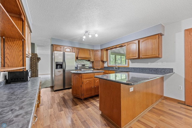 289 2nd St SW, Forman, ND 58032 - kitchen with stainless steel appliances, light wood finished floors, custom range hood, a peninsula, and brown cabinets