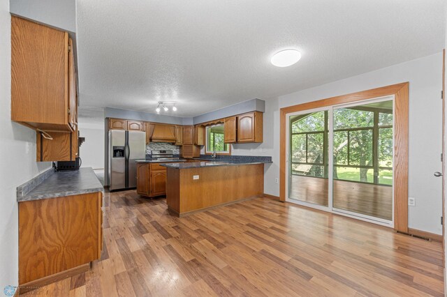 289 2nd St SW, Forman, ND 58032 - kitchen featuring stainless steel appliances, a peninsula, brown cabinets, dark countertops, and a textured ceiling
