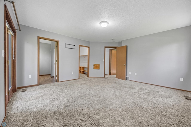 289 2nd St SW, Forman, ND 58032 - unfurnished bedroom with a textured ceiling, carpet flooring, a spacious closet, baseboards, and a closet