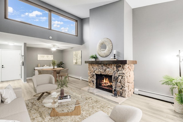 living area with wood finished floors, a baseboard radiator, a fireplace, and a high ceiling