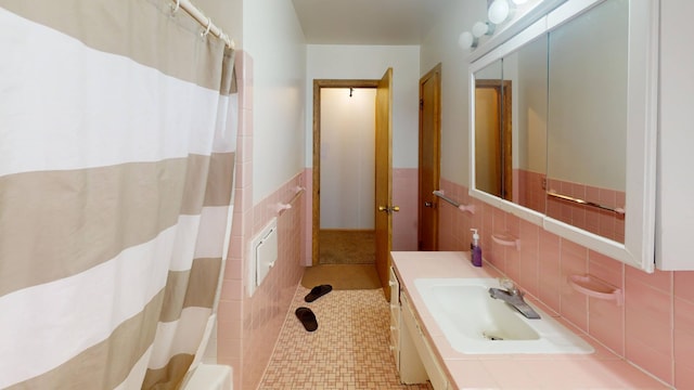 bathroom with a wainscoted wall, tile walls, and vanity