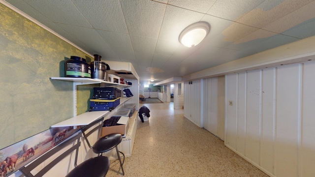 corridor with a drop ceiling and speckled floor