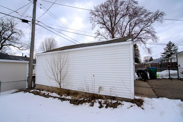 snow covered garage featuring fence