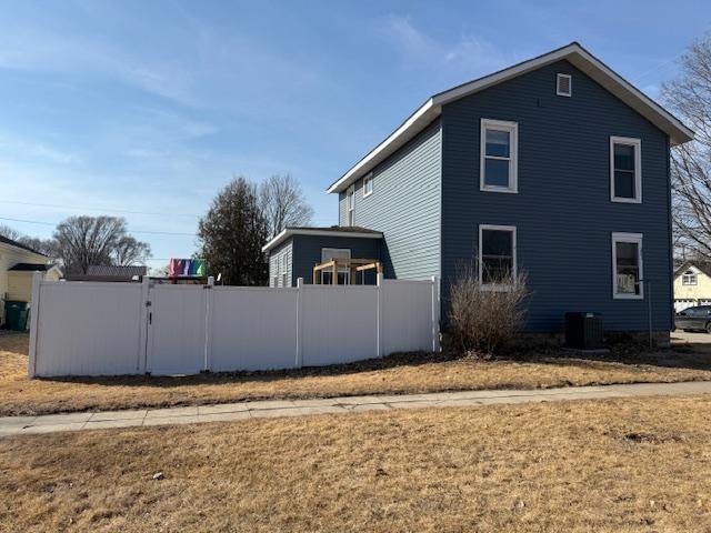 view of property exterior with cooling unit and fence